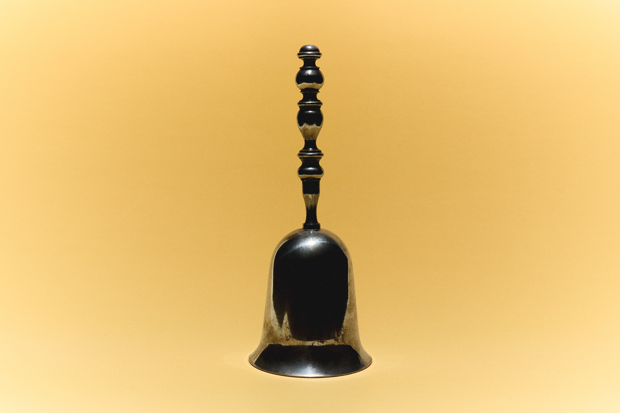 Clochette ancienne noire et or sur fond doré
